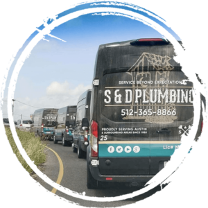 A rear view of a line of S & D Plumbing service vans along a road.