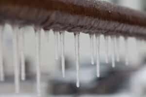 Close-up of small icicles hanging from a brown pipe.