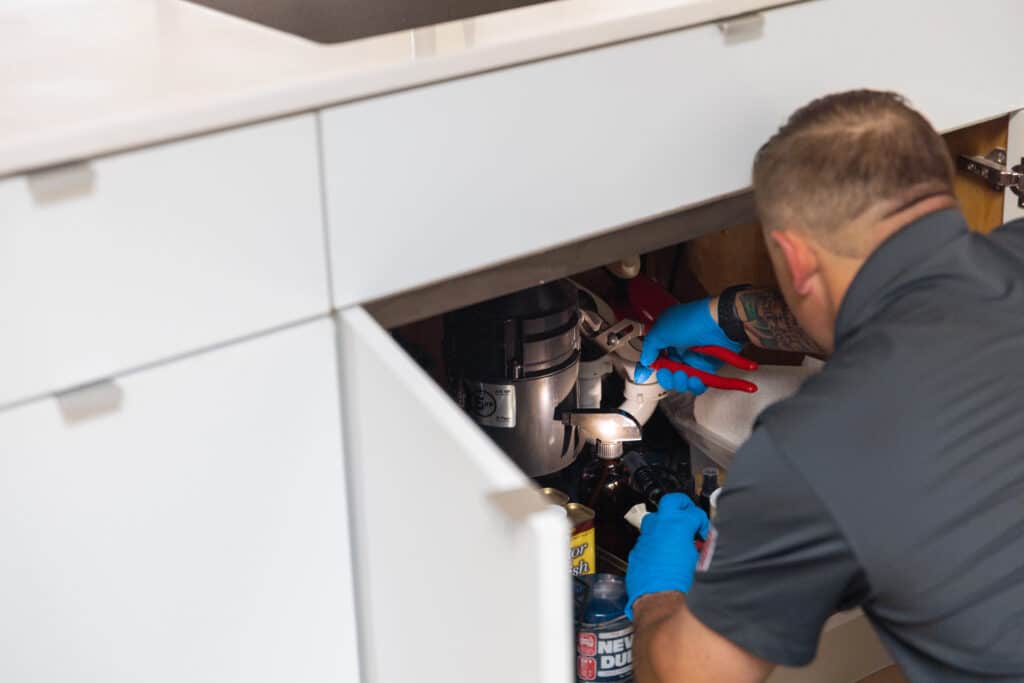 s and d plumbing technician inspecting a garbage disposal