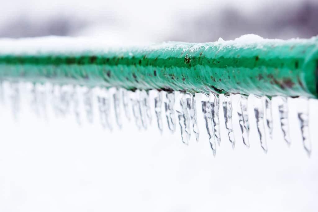 green frozen water pipe with icicles hanging off