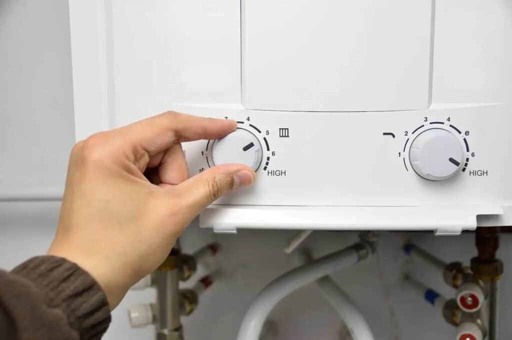 hand turning the dial on a tankless water heater